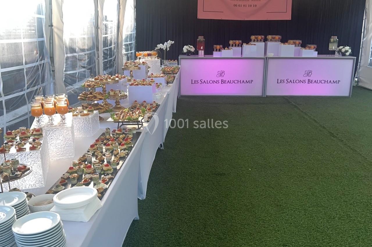 Location salle Beauchamp (Val-d'Oise) - Les Salons Beauchamp #9 Buffet de réception sous une tente avec tables garnies de plats variés et décoration élégante sur gazon synthétique.