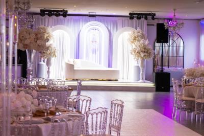 Miniature Location salle Beauchamp (Val-d'Oise) - Les Salons Beauchamp #1 Salle de réception élégante avec tables décorées de fleurs blanches, chaises transparentes et éclairage tamisé.