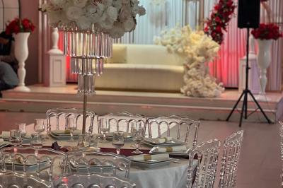 Miniature DECO 2025 Salle de réception élégante avec tables décorées de fleurs blanches, chaises transparentes et éclairage tamisé.