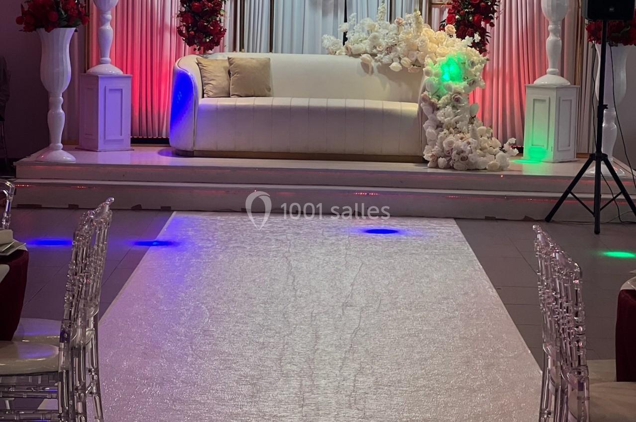 DECO 2025 Canapé blanc décoré de fleurs blanches et rouges, placé sur une scène avec rideaux et éclairages colorés.