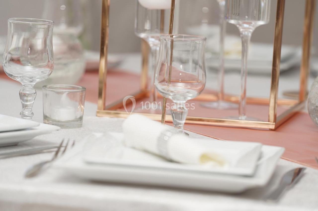 DECO DE TABLE Table dressée avec des assiettes blanches, des verres, des couverts et une décoration en métal doré.