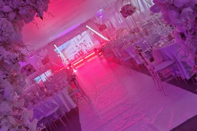 Miniature DECO ECRAN LED Salle de réception élégante avec tables décorées de fleurs blanches, chaises transparentes et éclairage tamisé.