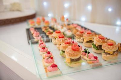 Miniature VIN D HONNEUR Salle de réception élégante avec tables décorées de fleurs blanches, chaises transparentes et éclairage tamisé.