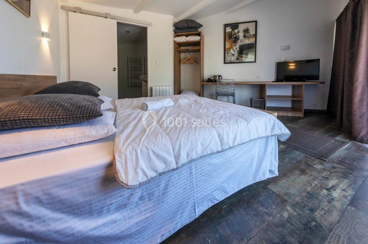 Location salle Saint-Aignan-de-Cramesnil (Calvados) - La Jalousie #20 Chambre lumineuse avec lit double, bureau, télévision, armoire ouverte et porte donnant sur une salle de bain.