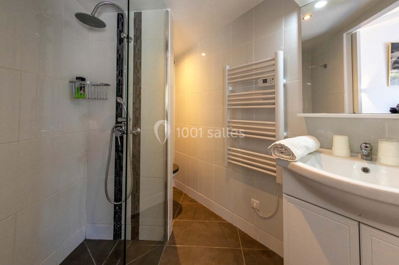 Location salle Saint-Aignan-de-Cramesnil (Calvados) - La Jalousie #27 Salle de bain moderne avec douche à l'italienne, lavabo avec miroir, radiateur sèche-serviettes et carrelage clair.