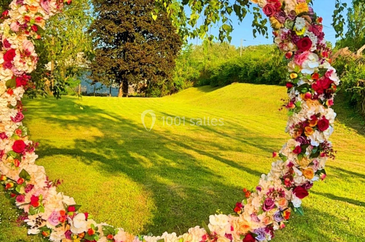 Arche circulaire ornée de fleurs colorées, installée sur une pelouse verdoyante par une journée ensoleillée.