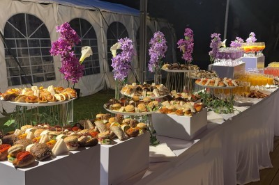Buffet en plein air avec une variété de plats et boissons, installé sous une tente lors d'un événement convivial.