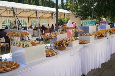 Buffet en plein air avec une variété de plats et boissons, installé sous une tente lors d'un événement convivial.
