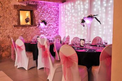 Miniature Location salle Vignieu (Isère) - Domaine de Suzel #7 Chambre avec lit rond, couverture rouge, pétales de rose, lampe de chevet et plafond en bois avec suspension plumeuse.