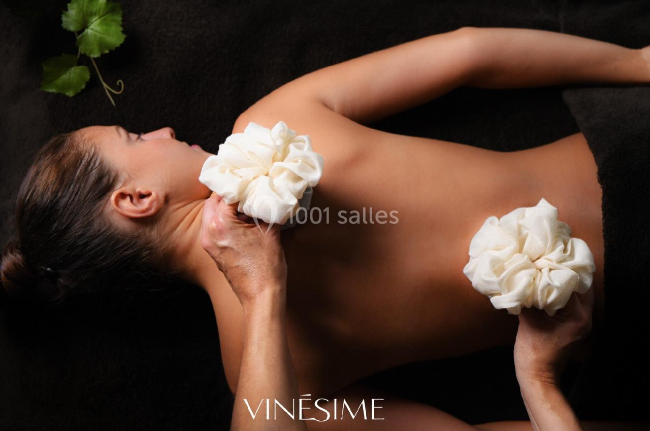 Location salle Vignieu (Isère) - Domaine de Suzel #23 Femme allongée sur le ventre recevant un massage avec des pochons en tissu sur le dos, sur un drap sombre.