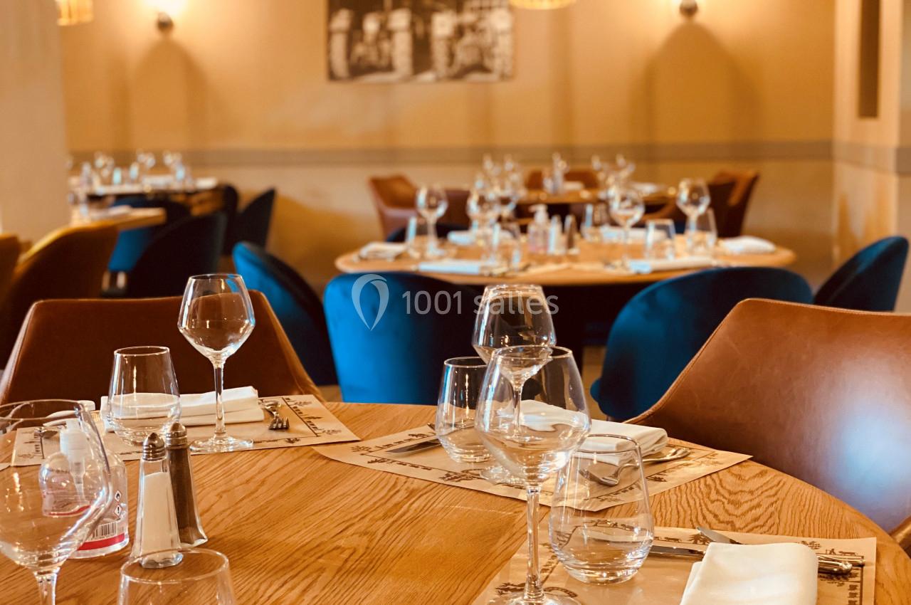 Location salle Vignieu (Isère) - Domaine de Suzel #18 Salle de restaurant élégante avec tables en bois dressées, verres et serviettes, éclairage chaleureux.