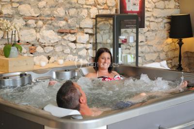 Miniature Location salle Vignieu (Isère) - Domaine de Suzel #9 Chambre avec lit rond, couverture rouge, pétales de rose, lampe de chevet et plafond en bois avec suspension plumeuse.
