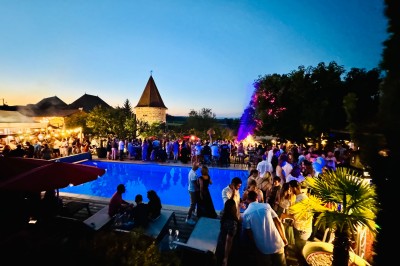 Miniature Location salle Vignieu (Isère) - Domaine de Suzel #46 Chambre avec lit rond, couverture rouge, pétales de rose, lampe de chevet et plafond en bois avec suspension plumeuse.