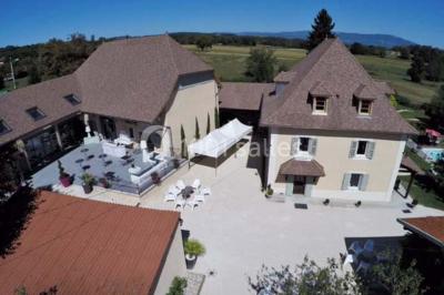 Miniature Location salle Vignieu (Isère) - Domaine de Suzel #5 Chambre avec lit rond, couverture rouge, pétales de rose, lampe de chevet et plafond en bois avec suspension plumeuse.