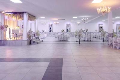 Salle de réception spacieuse avec piste de danse, éclairages colorés et équipement audio sur une estrade.