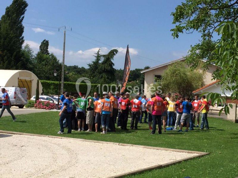 Location salle Vignieu (Isère) - Domaine de Suzel #14 Un groupe de personnes en gilets colorés participe à une activité en plein air sur une pelouse près de bâtiments.