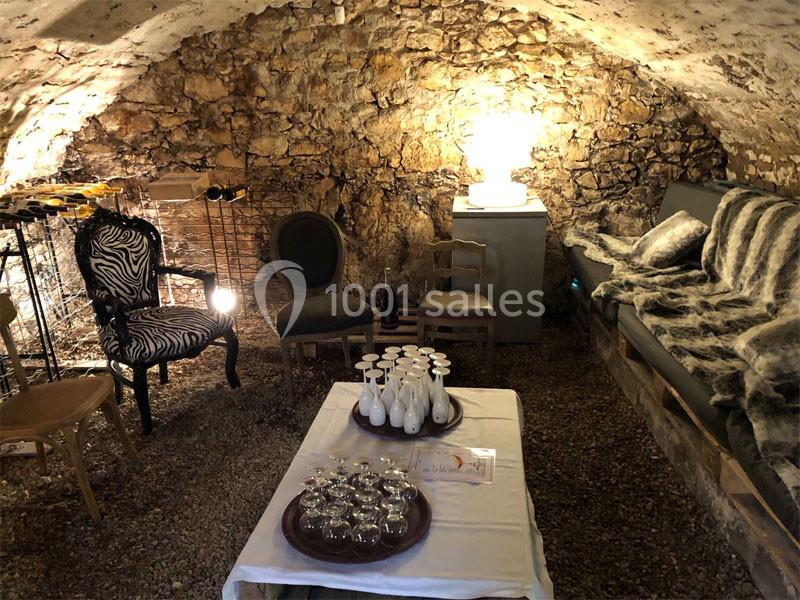 Location salle Vignieu (Isère) - Domaine de Suzel #7 Salle voûtée en pierre avec mobilier éclectique, table dressée de verres et carafes, éclairée par une lampe.