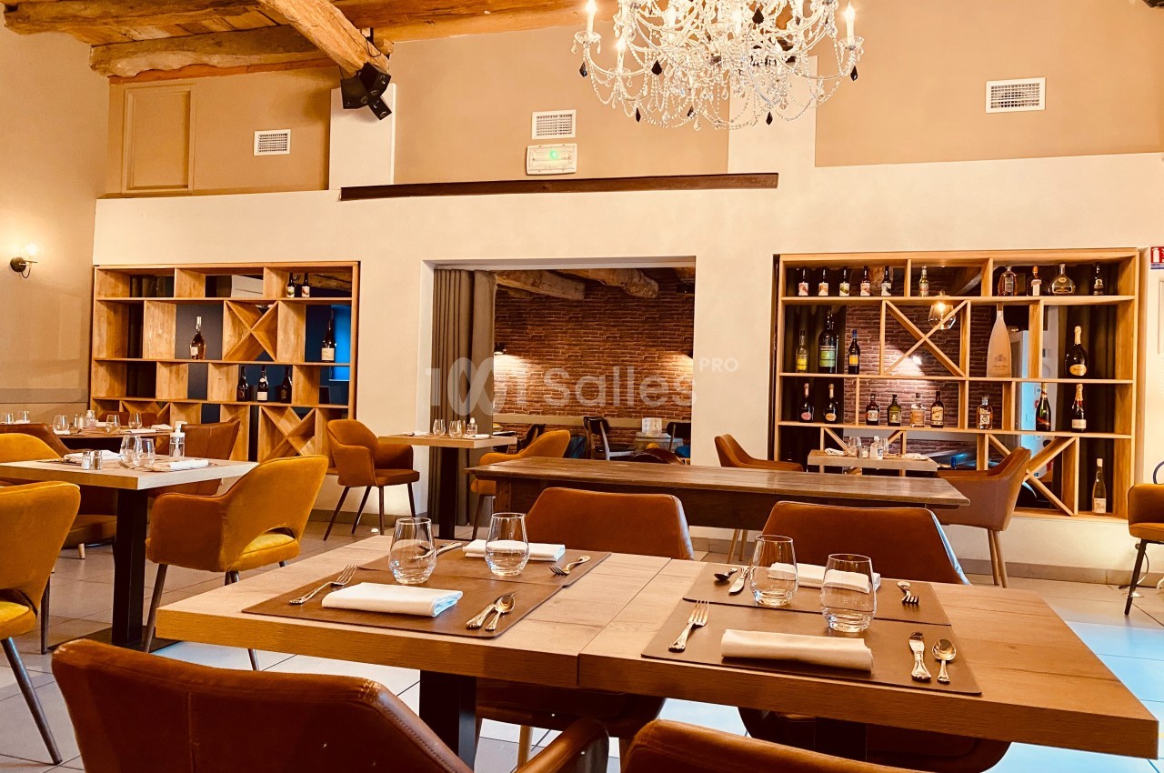 Salle de restaurant élégante avec tables en bois, chaises en cuir, étagères à bouteilles et lustre au plafond.