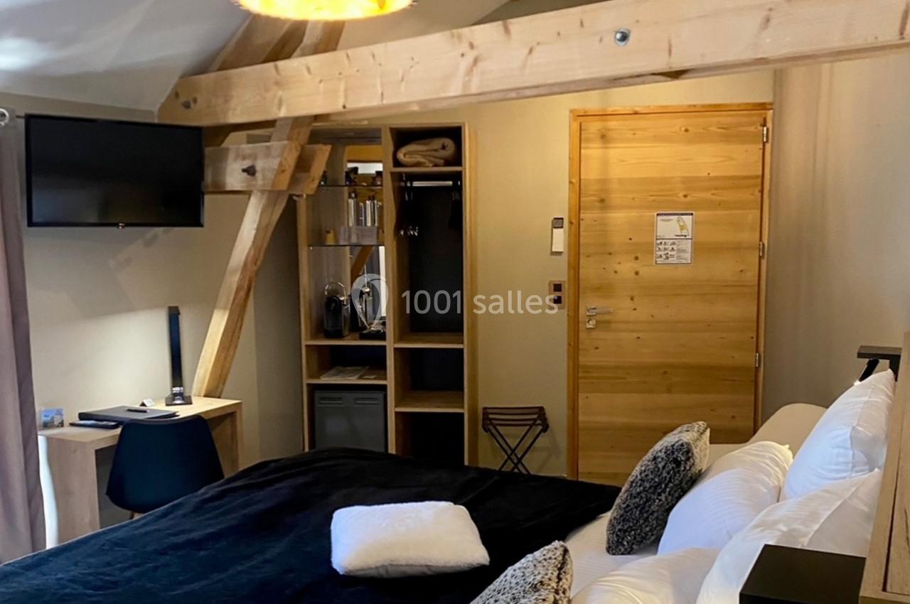 Location salle Vignieu (Isère) - Domaine de Suzel #39 Chambre avec poutres apparentes, lit double, bureau, télévision murale et espace de rangement en bois clair.