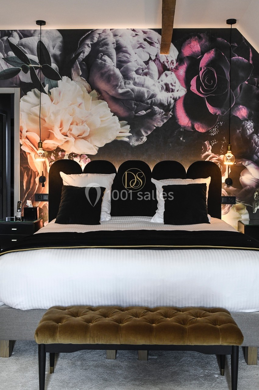 Location salle Vignieu (Isère) - Domaine de Suzel #42 Lit double avec tête de lit noire, coussins noirs et mur décoré d'une fresque florale sombre dans une chambre élégante.