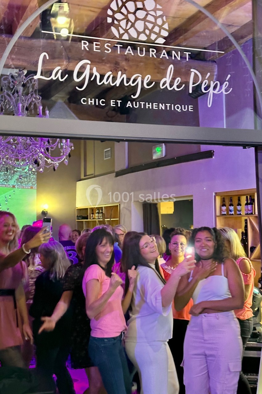 Location salle Vignieu (Isère) - Domaine de Suzel #44 Des personnes souriantes dansent et s'amusent à l'intérieur d'un restaurant sous une enseigne lumineuse.