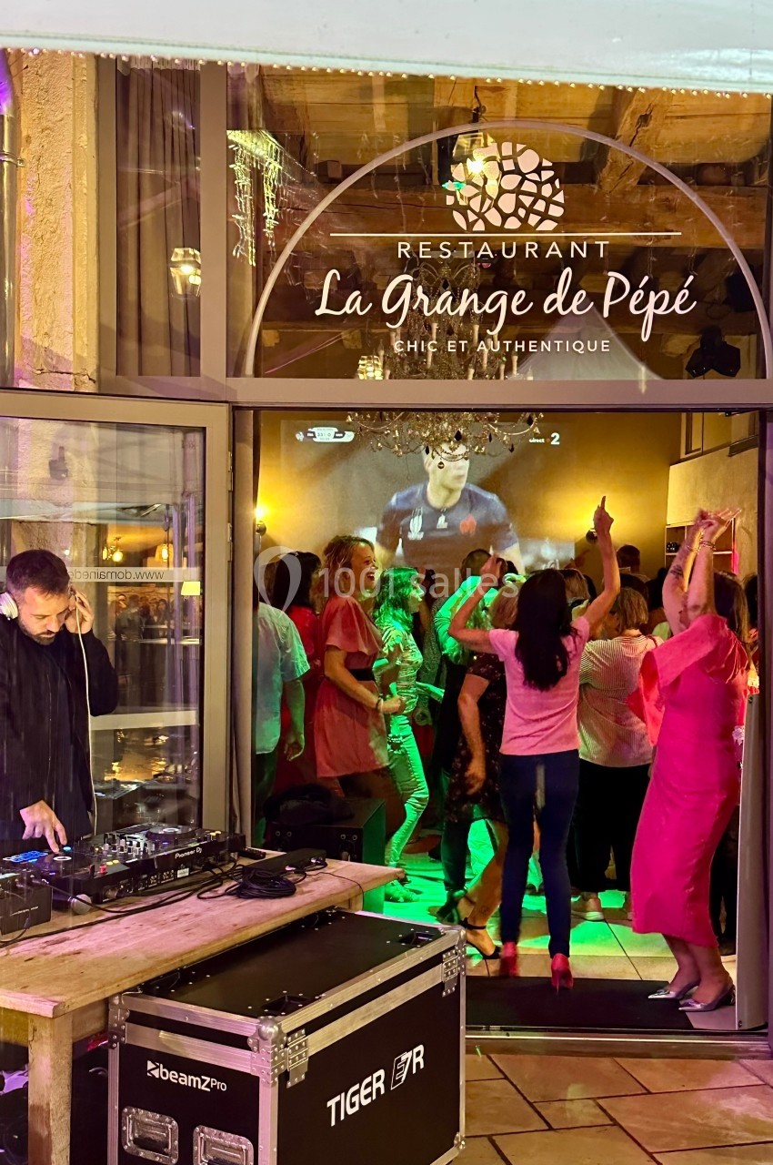 Location salle Vignieu (Isère) - Domaine de Suzel #45 Des personnes dansent à l'intérieur d'un restaurant, avec un DJ jouant de la musique à l'extérieur près de l'entrée.