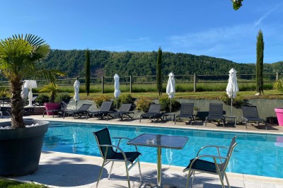 Vue aérienne d'un domaine rural avec des bâtiments, une tente beige, des espaces verts et des participants dispersés.