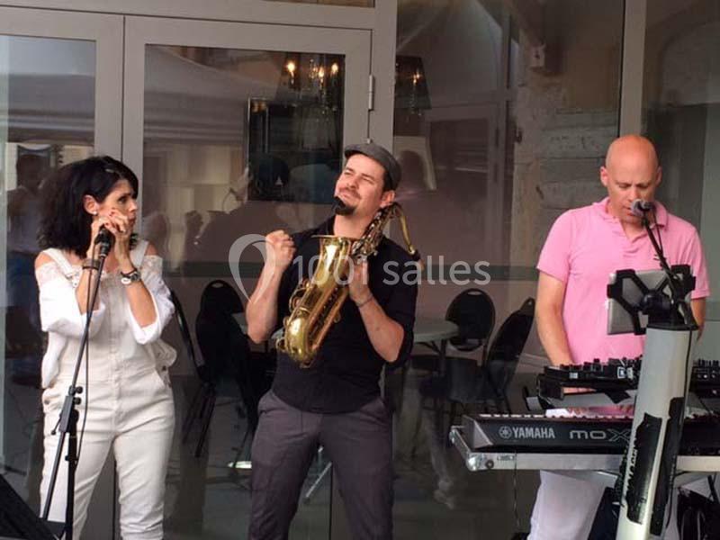Location salle Vignieu (Isère) - Domaine de Suzel #9 Trois musiciens jouent en extérieur : une chanteuse, un saxophoniste et un claviériste.