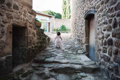 Chambre avec un lit double, draps rayés verts, table de chevet en bois, lampes et sol carrelé beige.