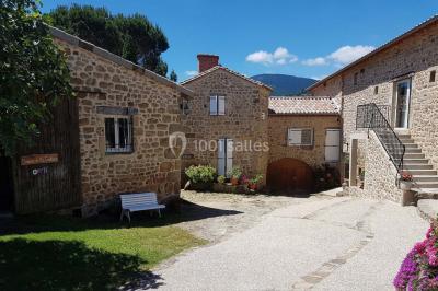 Chambre avec un lit double, draps rayés verts, table de chevet en bois, lampes et sol carrelé beige.