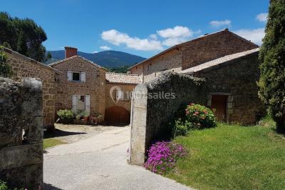 Chambre avec un lit double, draps rayés verts, table de chevet en bois, lampes et sol carrelé beige.