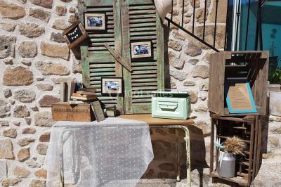 Chambre avec un lit double, draps rayés verts, table de chevet en bois, lampes et sol carrelé beige.