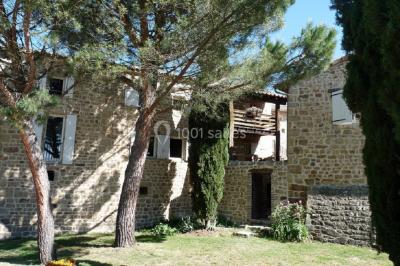 Chambre avec un lit double, draps rayés verts, table de chevet en bois, lampes et sol carrelé beige.