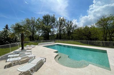 Chambre avec un lit double, draps rayés verts, table de chevet en bois, lampes et sol carrelé beige.