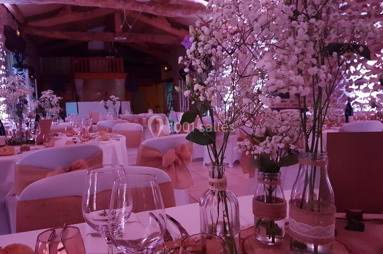 Salle de réception décorée avec des fleurs blanches, des tables dressées et une ambiance lumineuse tamisée.