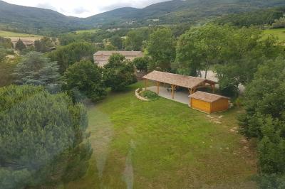 Chambre avec un lit double, draps rayés verts, table de chevet en bois, lampes et sol carrelé beige.