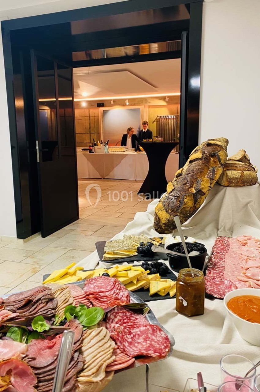 Plateau de charcuterie, fromages, pain et condiments disposés sur une table lors d'un événement en intérieur.
