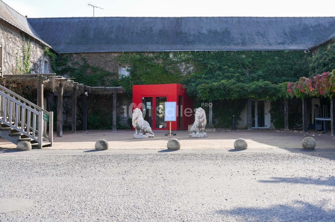 Entrée d'un bâtiment avec une structure rouge, deux statues de lions et des murs recouverts de végétation.