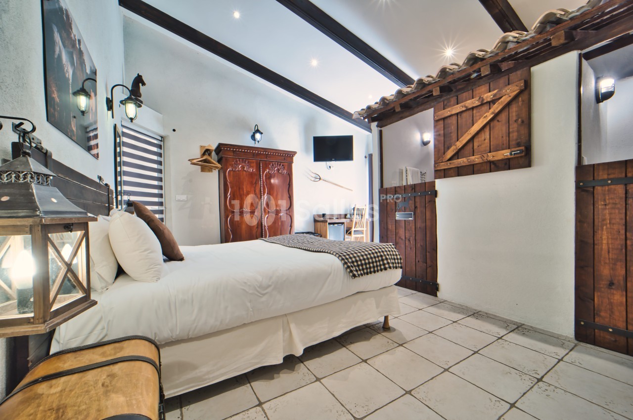 Chambre lumineuse avec lit double, armoire en bois, bureau, télévision murale et décoration rustique.