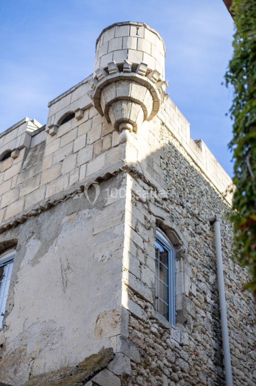 Tour d'angle en pierre d'un bâtiment ancien avec des fenêtres et un ciel bleu en arrière-plan.