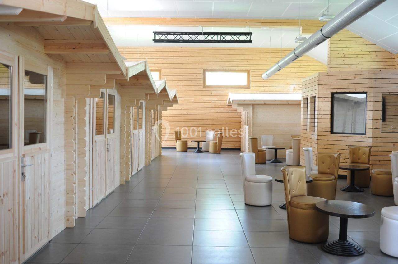 Salle lumineuse avec cabines en bois, sièges rembourrés et tables basses sur un sol carrelé gris.