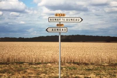 Panneau de signalisation indiquant les directions vers Aunay-sous-Auneau et Auneau, devant un champ de blé sous un ciel…