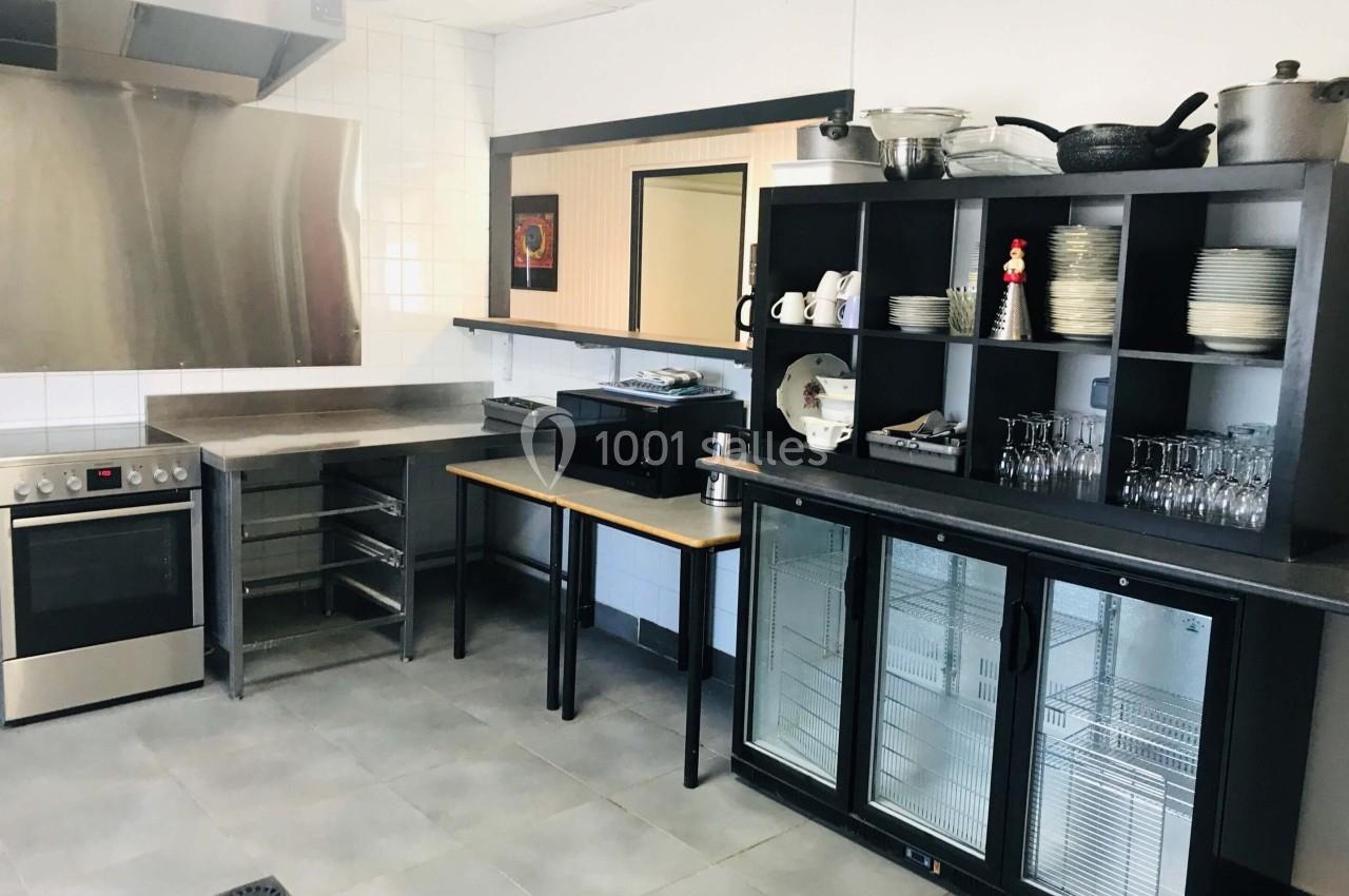 Cuisine équipée avec four, plaques de cuisson, étagères de rangement, vaisselle, micro-ondes et réfrigérateurs vitrés.