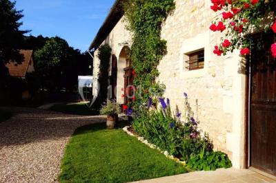 Chambre lumineuse avec deux lits simples, sol en carrelage, plafond en bois, et vue sur un jardin depuis une porte ouverte.