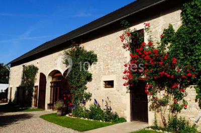 Chambre lumineuse avec deux lits simples, sol en carrelage, plafond en bois, et vue sur un jardin depuis une porte ouverte.