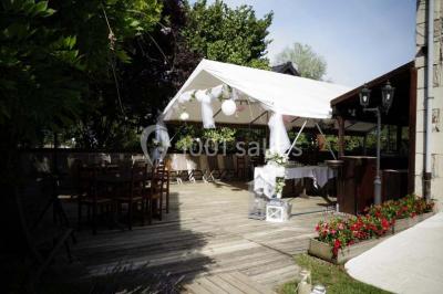 Chambre lumineuse avec deux lits simples, sol en carrelage, plafond en bois, et vue sur un jardin depuis une porte ouverte.