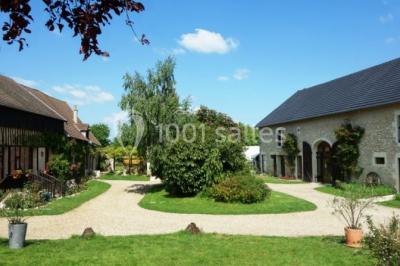 Chambre lumineuse avec deux lits simples, sol en carrelage, plafond en bois, et vue sur un jardin depuis une porte ouverte.