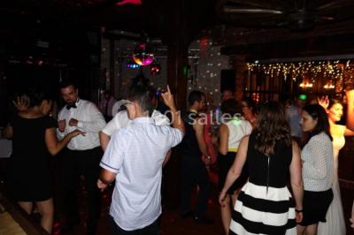 Chambre lumineuse avec deux lits simples, sol en carrelage, plafond en bois, et vue sur un jardin depuis une porte ouverte.
