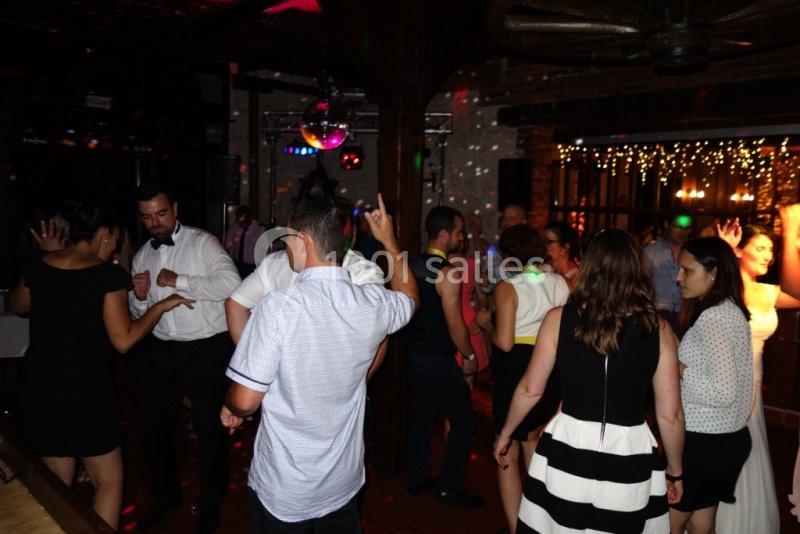 Des personnes dansent et discutent dans une salle sombre éclairée par des lumières colorées et une boule disco.