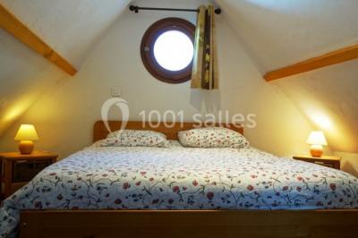 Chambre lumineuse avec deux lits simples, sol en carrelage, plafond en bois, et vue sur un jardin depuis une porte ouverte.